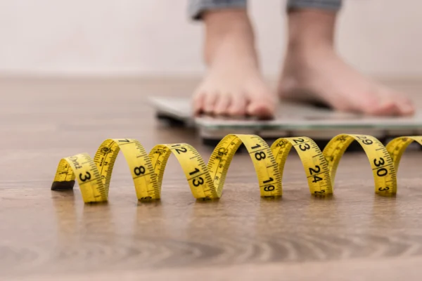 Woman-on-Scales-with-Tape-Measure-scaled