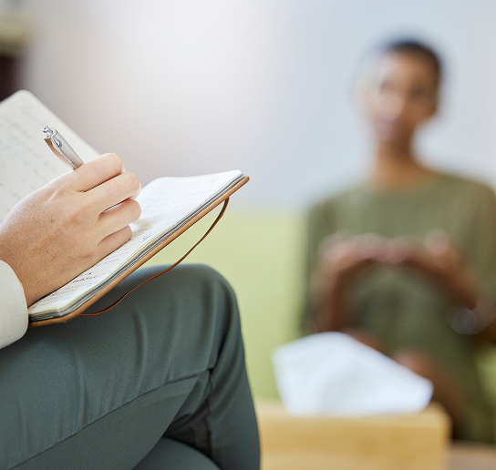 A doctor writing in their journal whilst delivering a patient mental health assessment