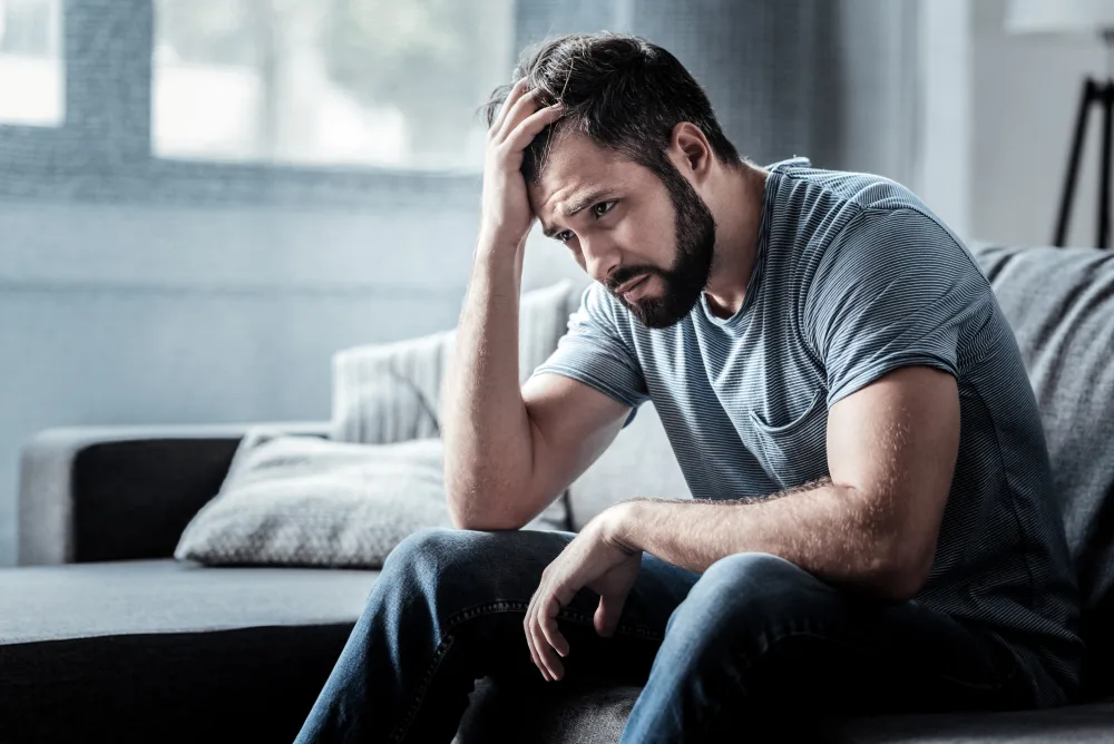 a man sat on a couch looking overwhelmed and depressed