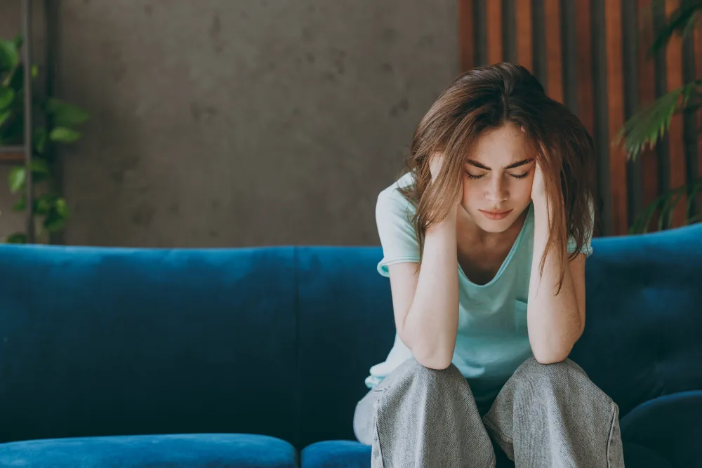 a woman sat on couch looking stressed