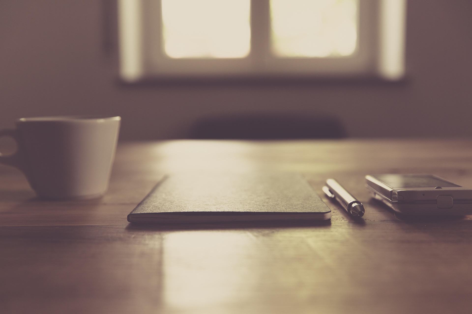 pen and paper on table with mug and phone