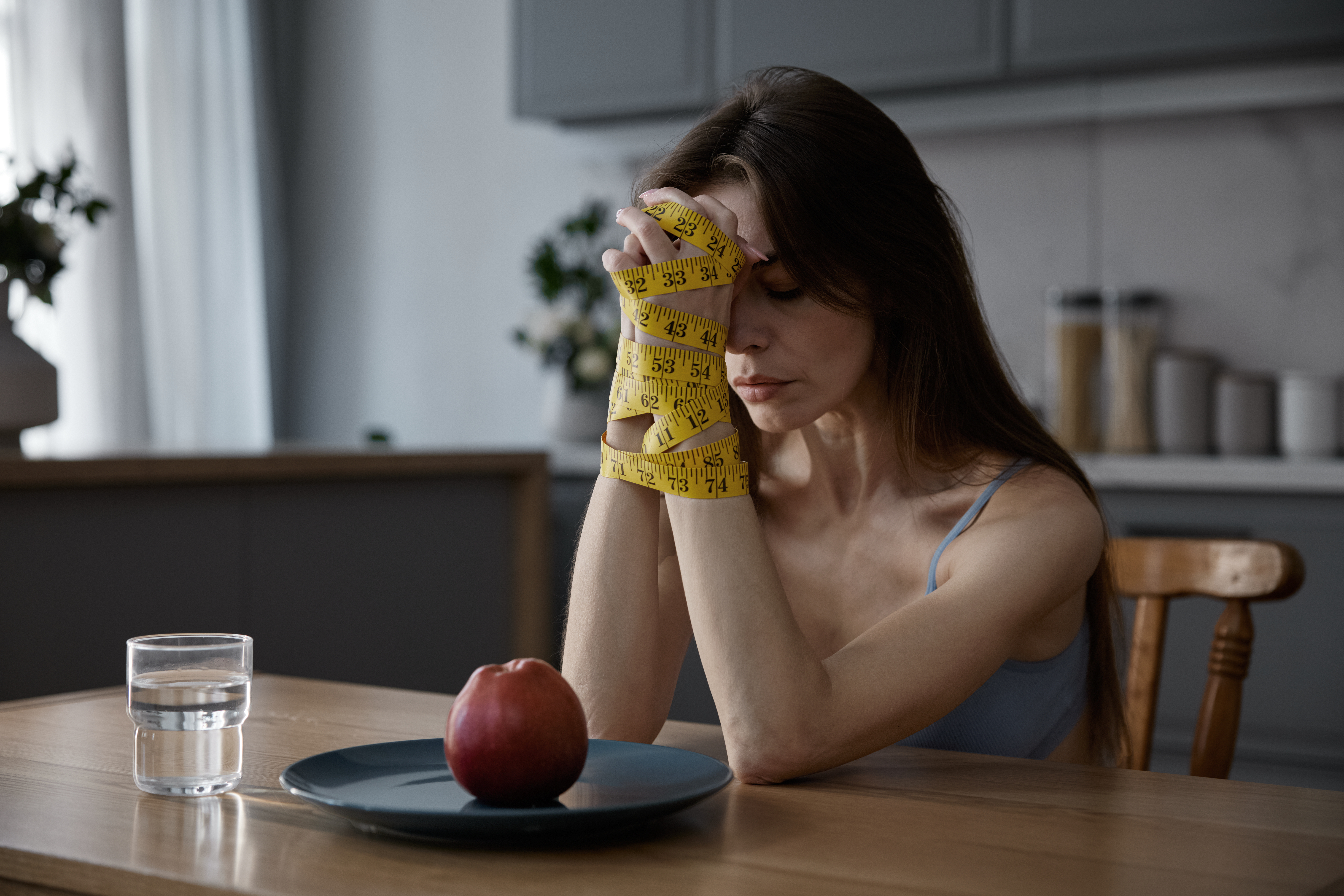 Tied Female Hands with Tape Measure looking sad at apple